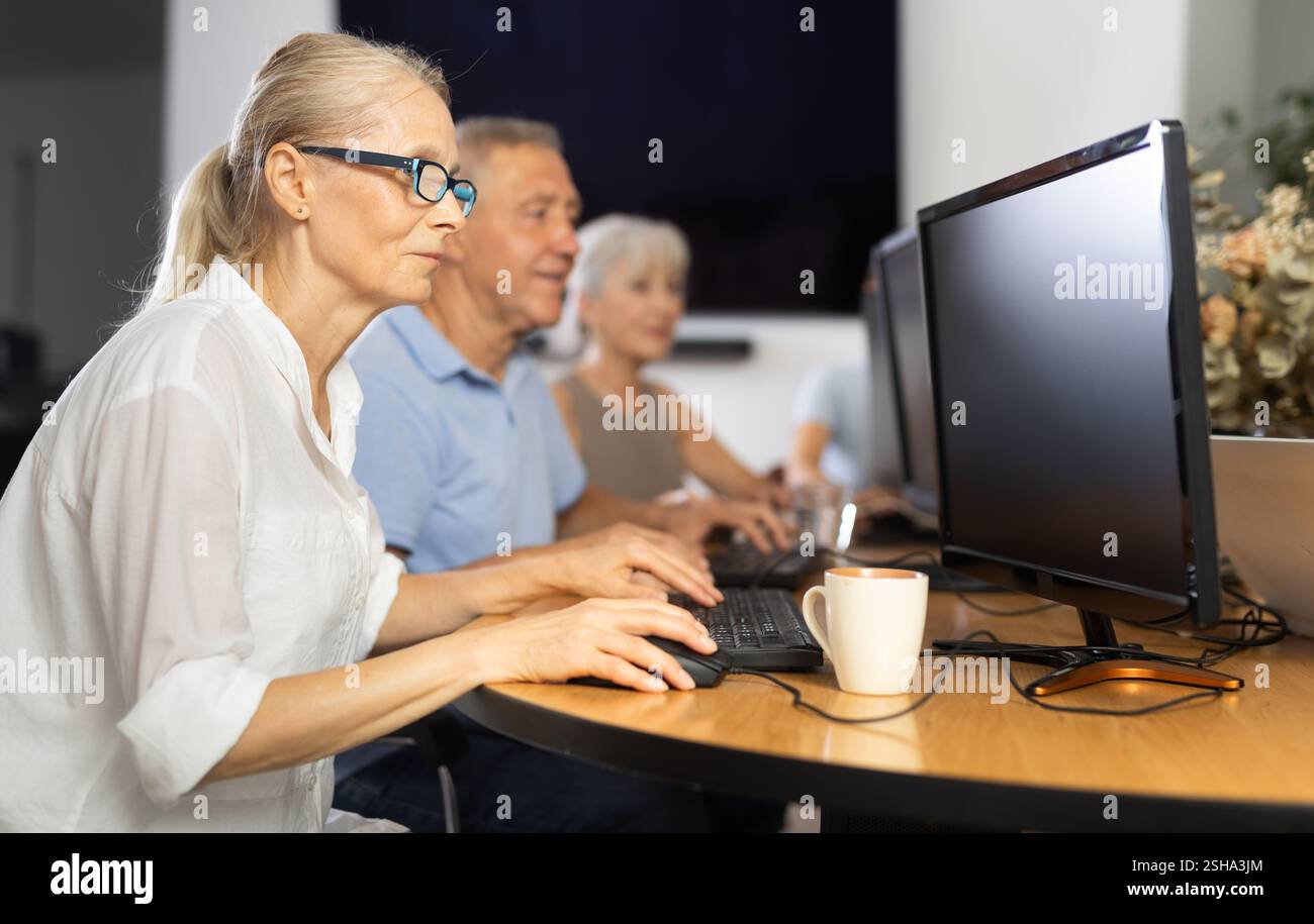 Old woman learning computer programs in training room Stock Photo