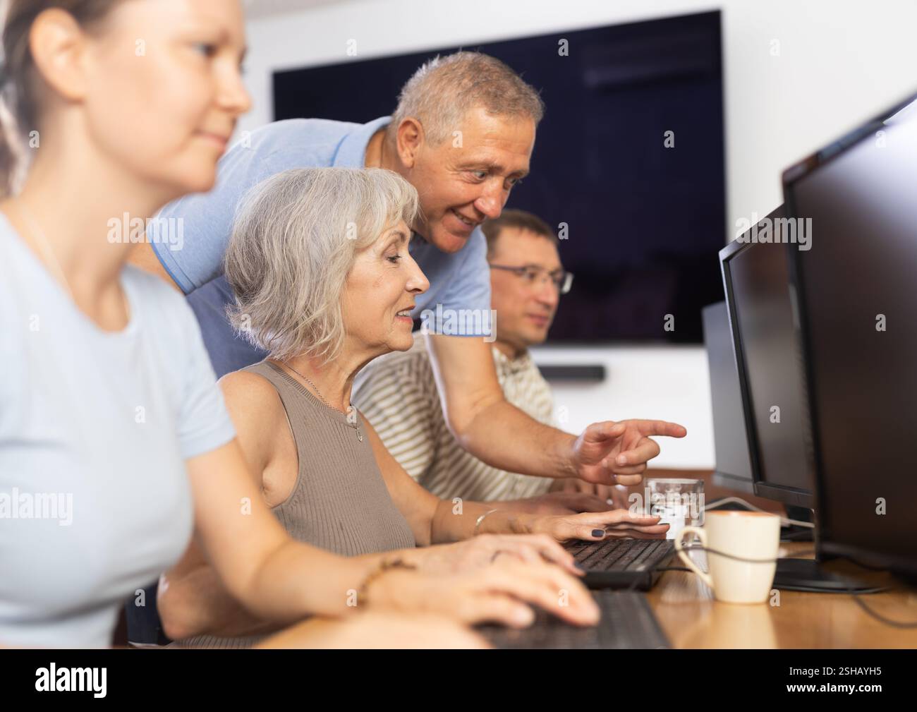 Older mentor explaining something to elderly woman during computer class Stock Photo