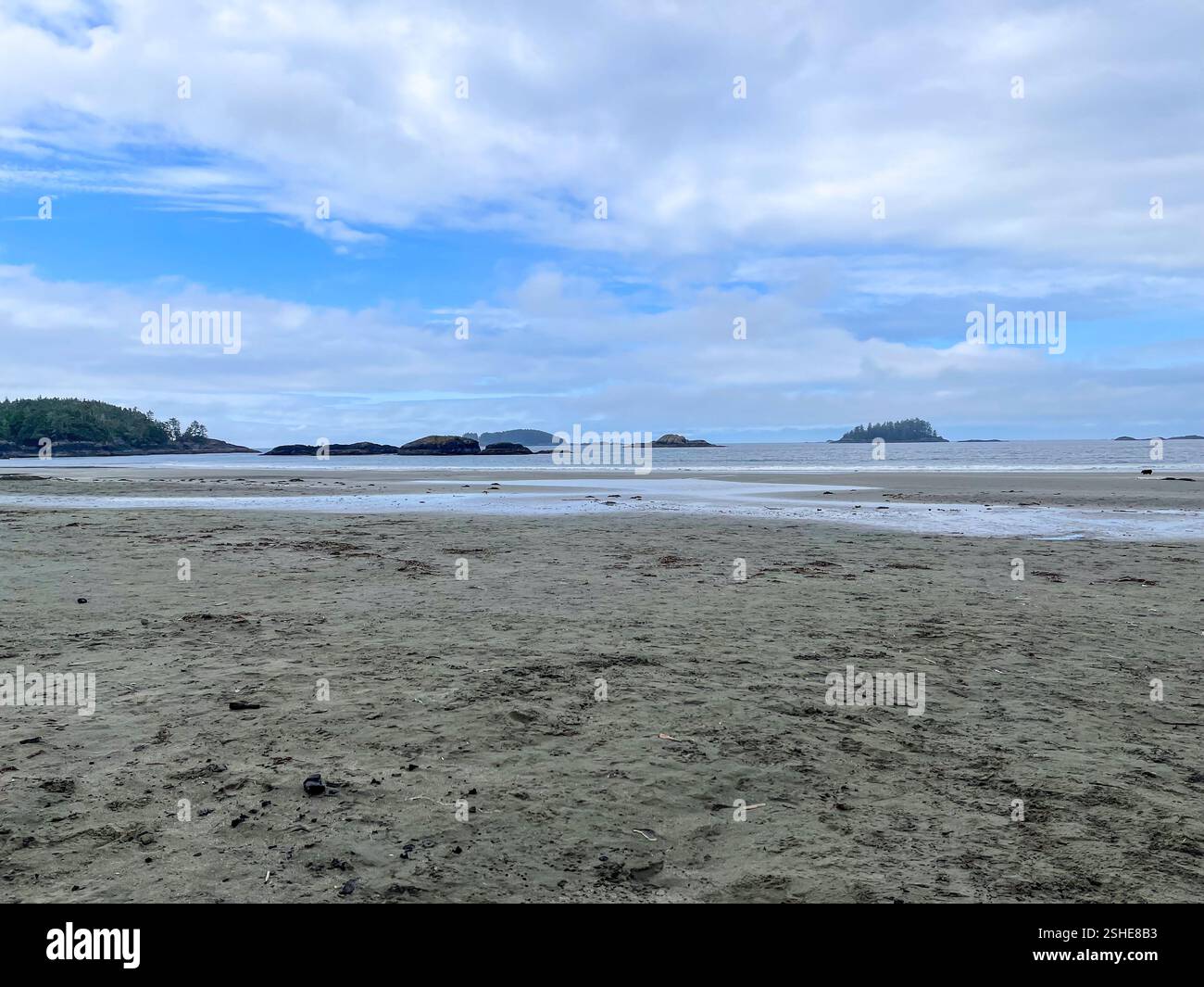 A beach at low tide with exposed rocky outcrops and distant islands. Perfect for eco-tourism, travel, and coastal scenery themes. - Smartphone Captured Stock Image
