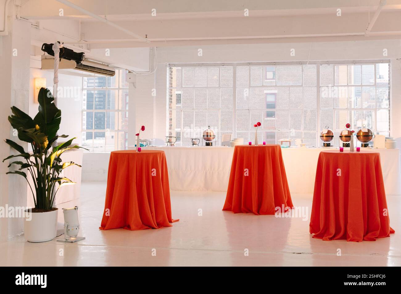 Bright indoor space with orange-clothed tables prepared for an elegant ...