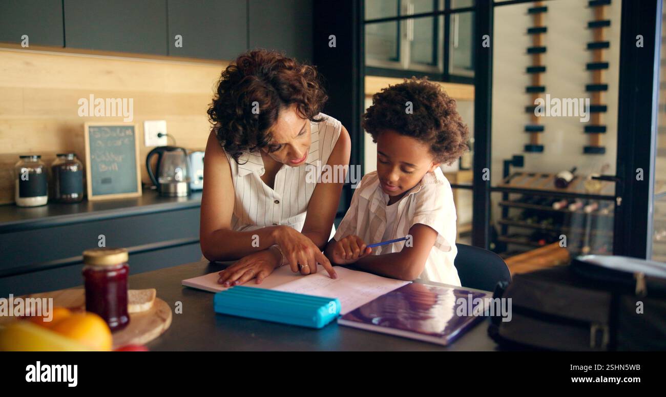 Mother, homework and child learning with books in kitchen for education ...