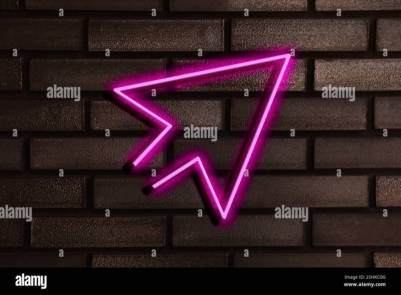 Pink neon arrow-shaped pointer on brick wall Stock Photo