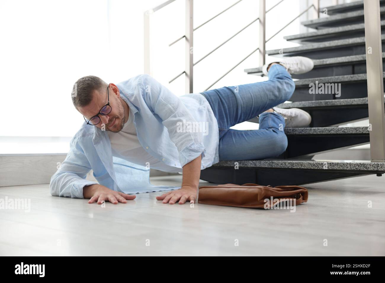 Injured man on stairs in building after fall. Dangerous accident Stock ...