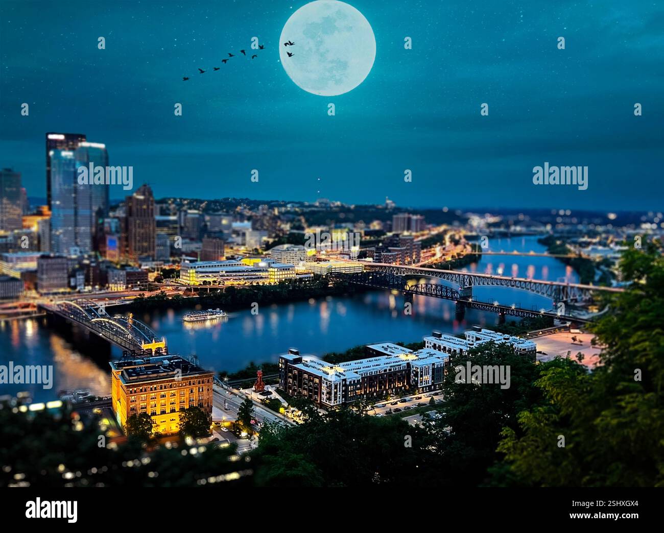 Pittsburgh at night. A view overlooking downtown Pittsburgh, Pennsylvania, at night. City skyline with a large moon in the sky. Stock Photo
