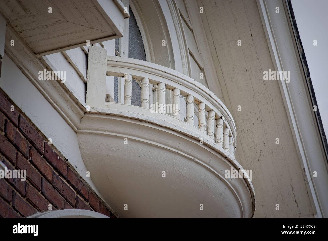 Wood and concrete balcony in front of upper level window on old brick building Stock Photo