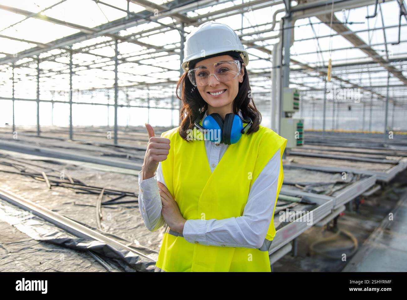 Smiling caucasian young female engineer in protective glasses Stock Photo