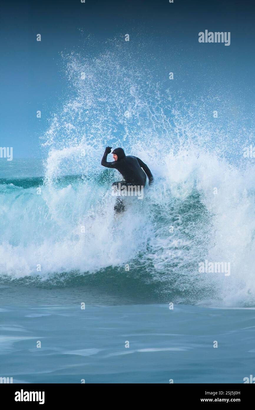 A surfer riding a wave at Fistral in Newquay in Cornwall in the UK ...