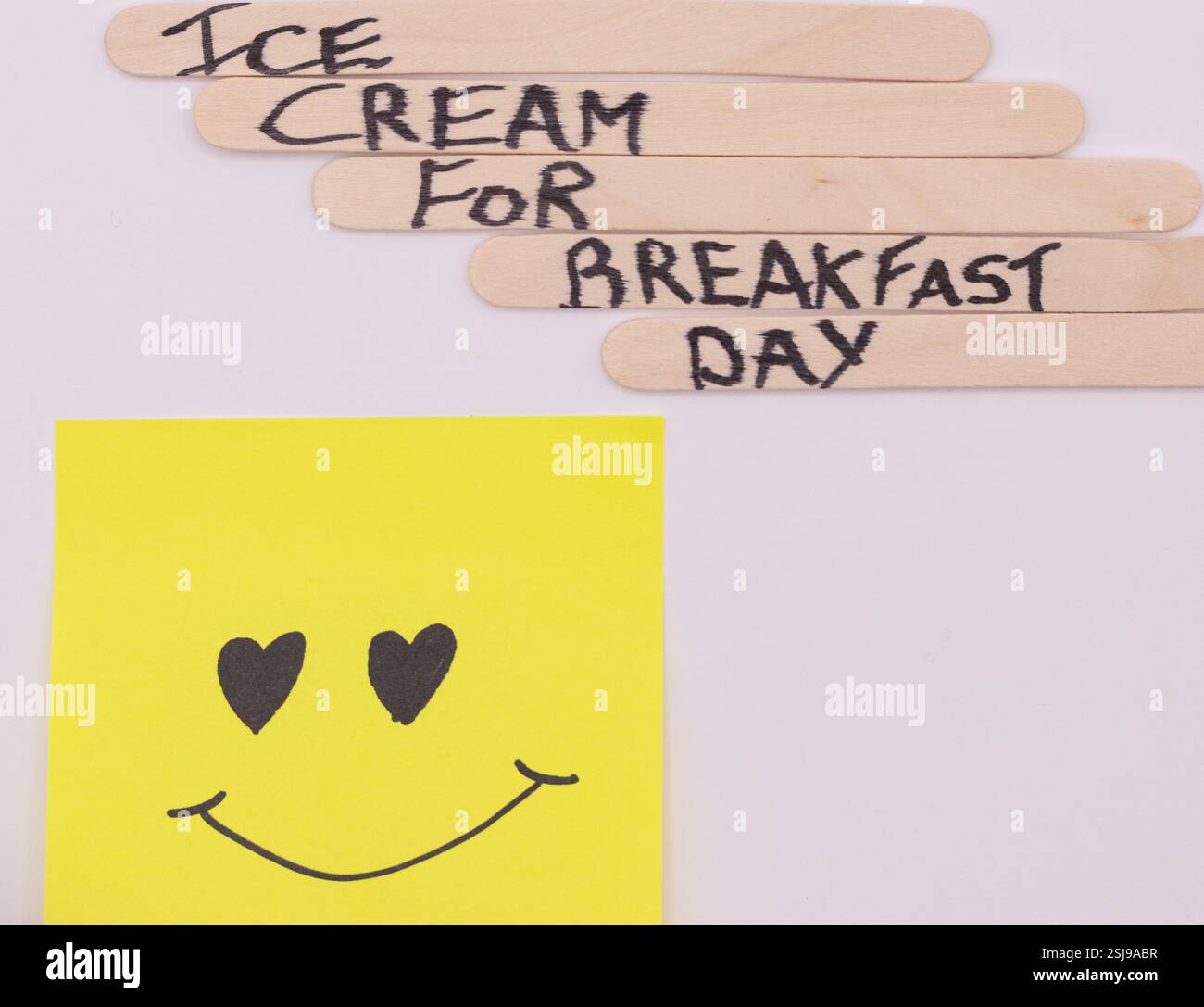 A concept of handwritten popsicle sticks with a heart emoticon on a ...