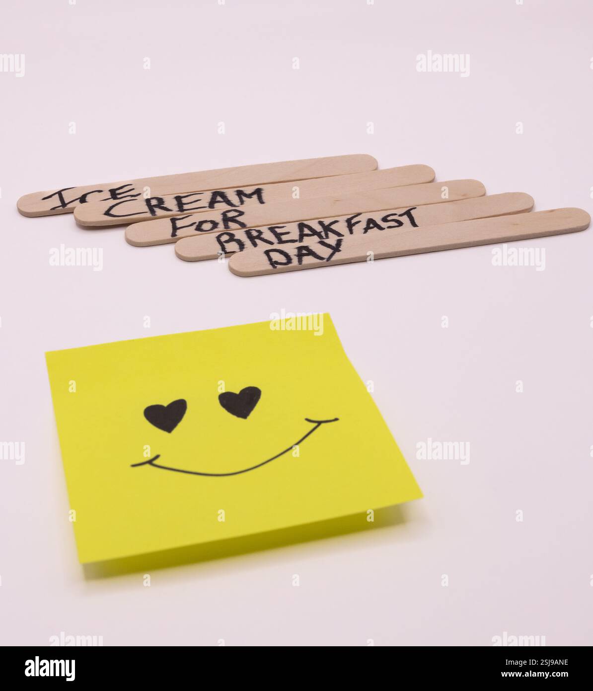A concept of handwritten popsicle sticks with a heart emoticon on a ...