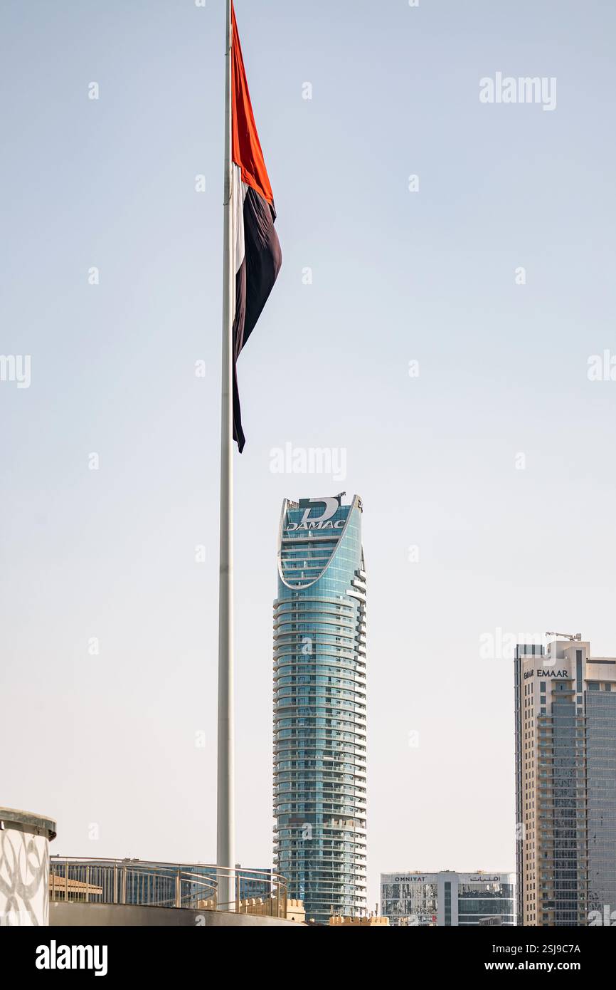 Flag of the United Arab Emirates and Glass skyscraper with Damac development company logo. High building, cityscape. DAMAC Maison Distinction hotel to Stock Photo