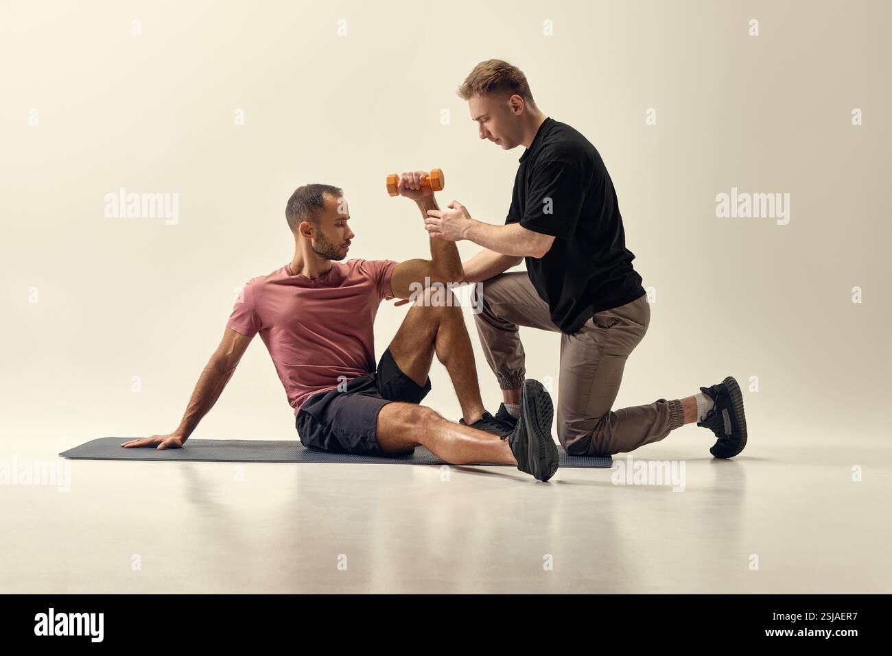 Trainer helping man perform seated dumbbell curl, guiding arm movement ...