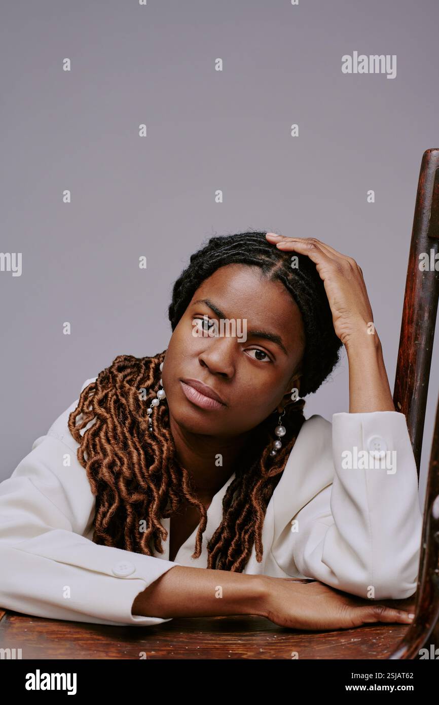 Portrait of African American woman leaning on wooden chair, wearing ...