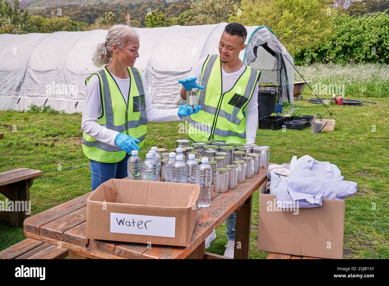 Two volunteers packaging donation boxes at table outdoors Stock Photo