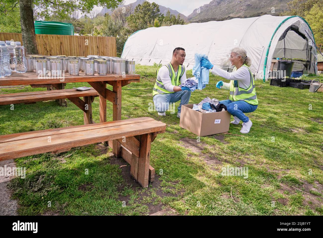 Two volunteers packaging donation boxes at table outdoors Stock Photo