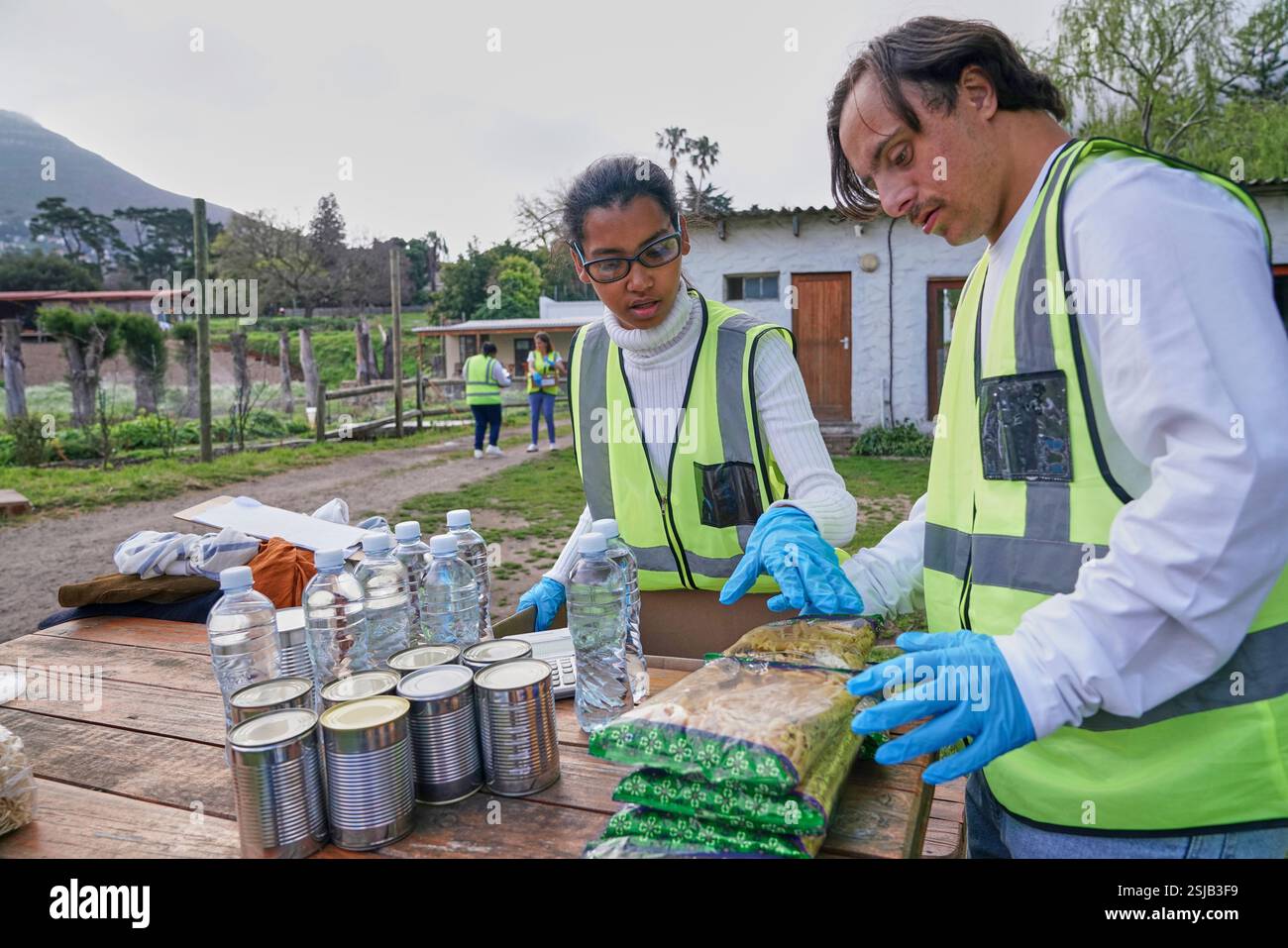 Two volunteers packaging donation boxes at table outdoors Stock Photo
