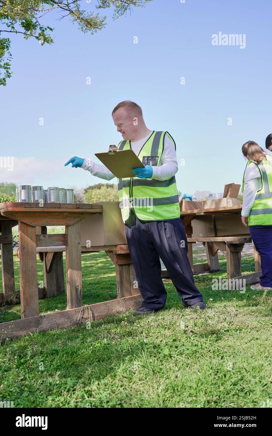 Two volunteers packaging donation boxes at table outdoors Stock Photo