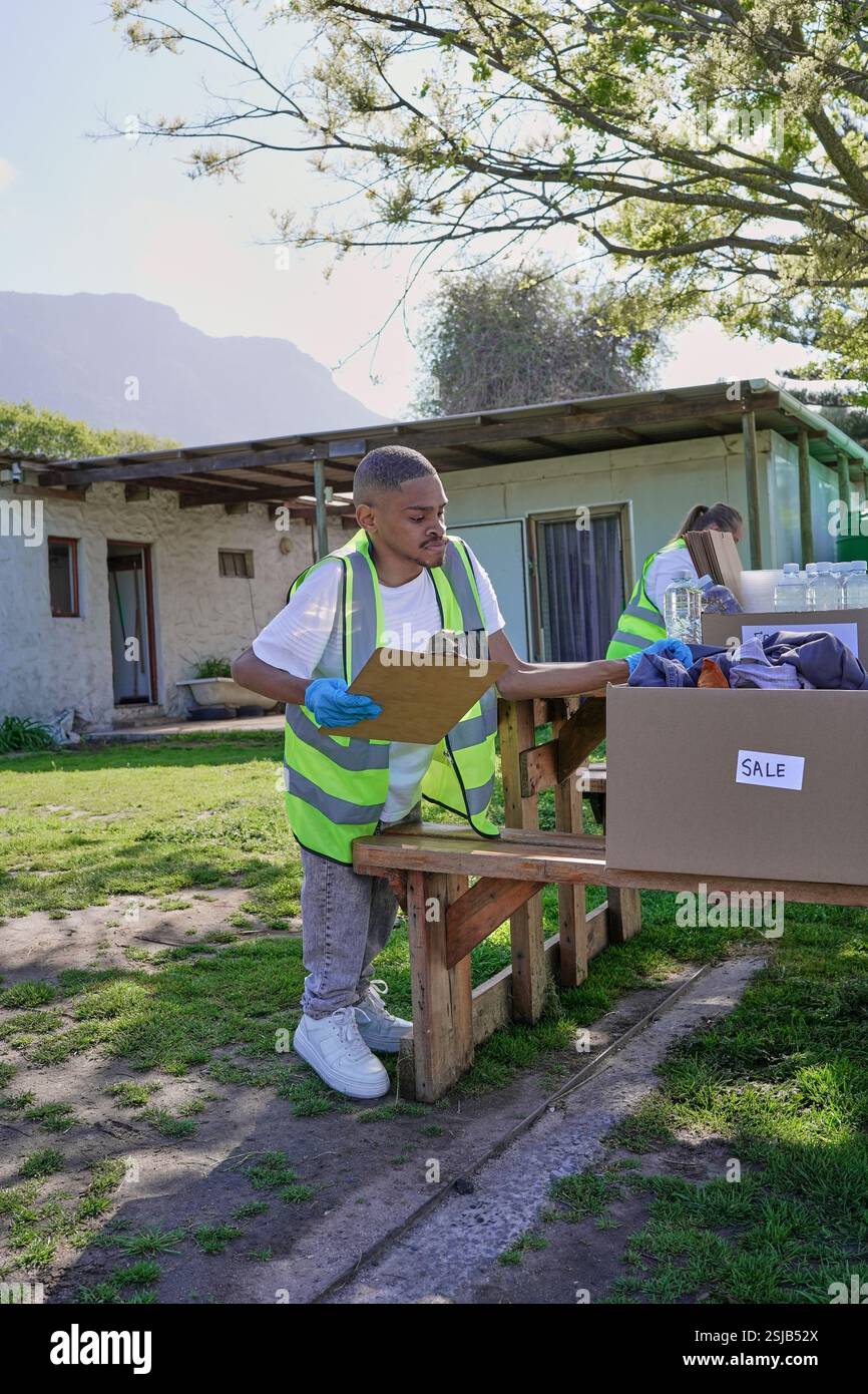 Two volunteers packaging donation boxes at table outdoors Stock Photo