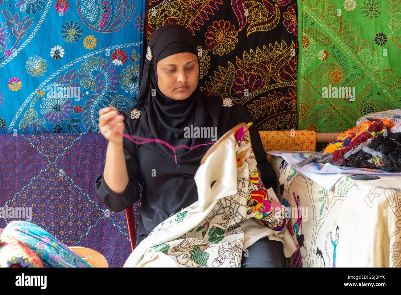 A woman skillfully crafts Nakshi Kantha, a traditional embroidered ...
