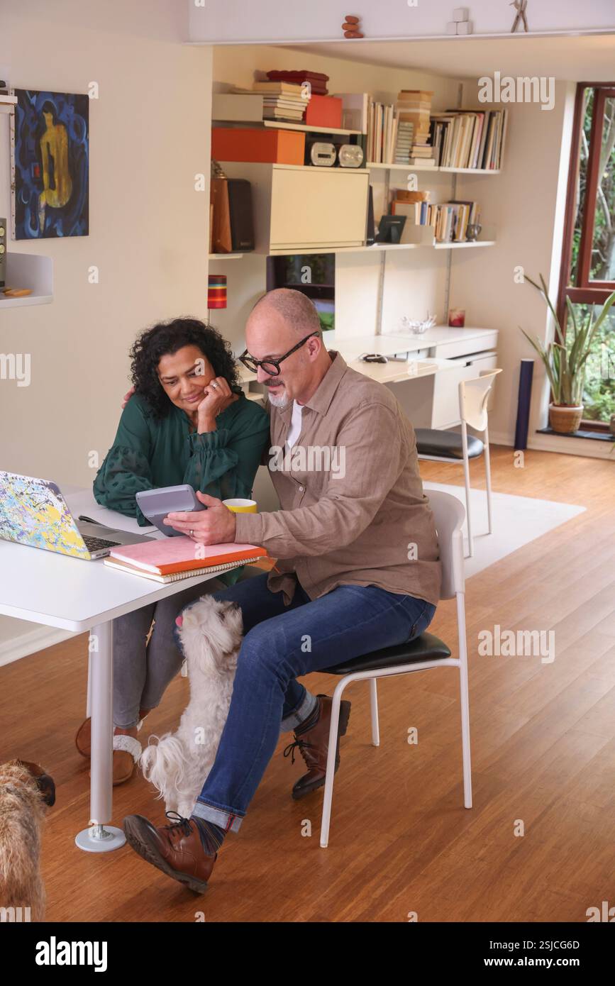 Couple using calculator in front of laptop Stock Photo