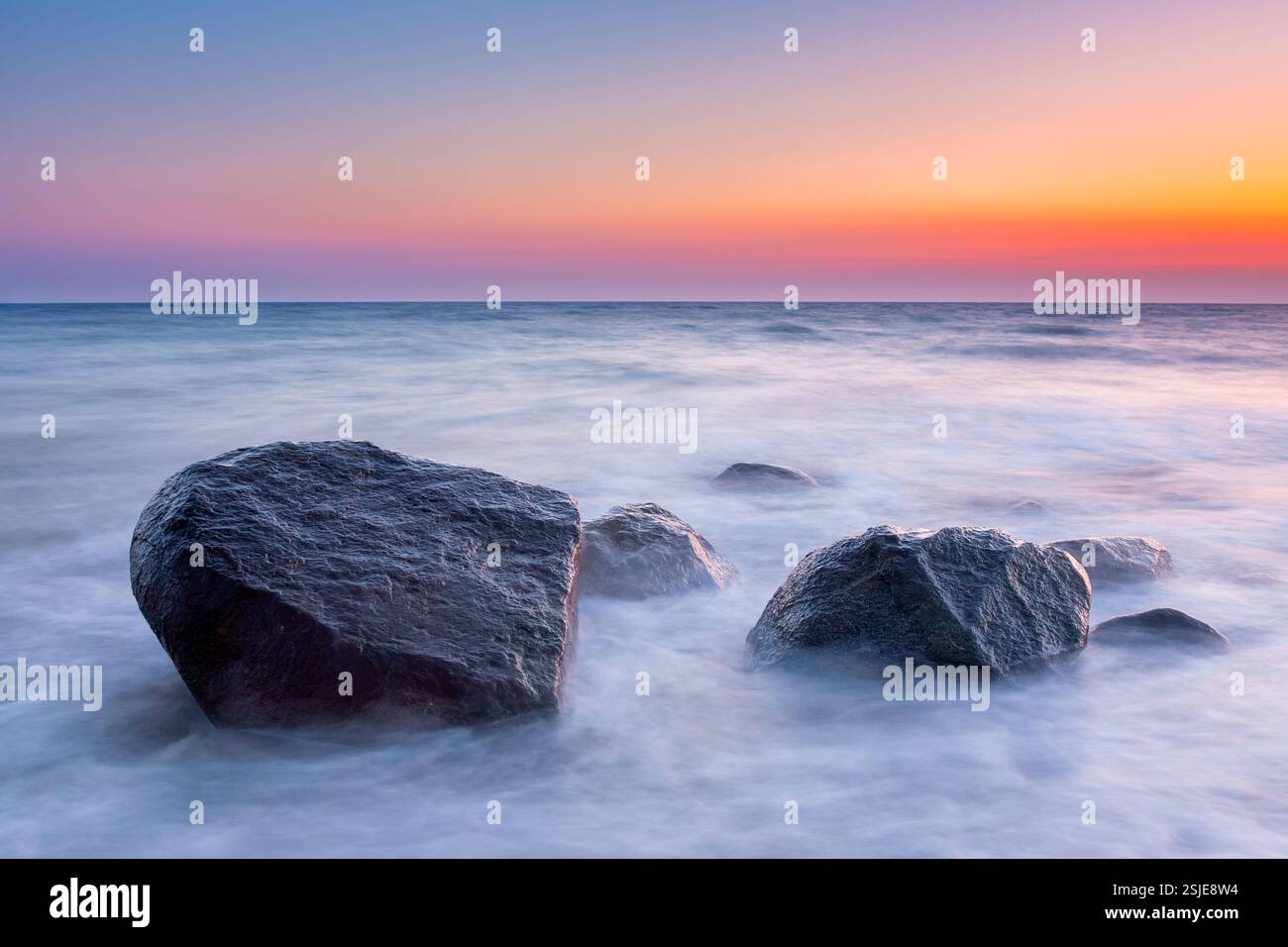 Large boulders in surf at Brodtener Ufer / Brodten Steilufer, cliff in the Bay of Lübeck along the Baltic Sea at sunrise, Schleswig-Holstein, Germany Stock Photo