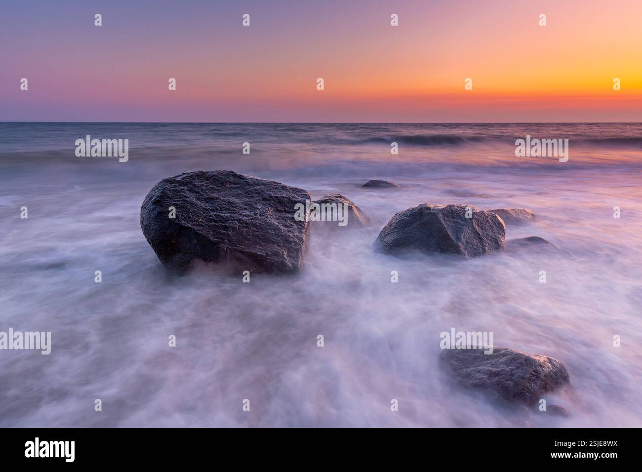 Large boulders in surf at Brodtener Ufer / Brodten Steilufer, cliff in the Bay of Lübeck along the Baltic Sea at sunrise, Schleswig-Holstein, Germany Stock Photo