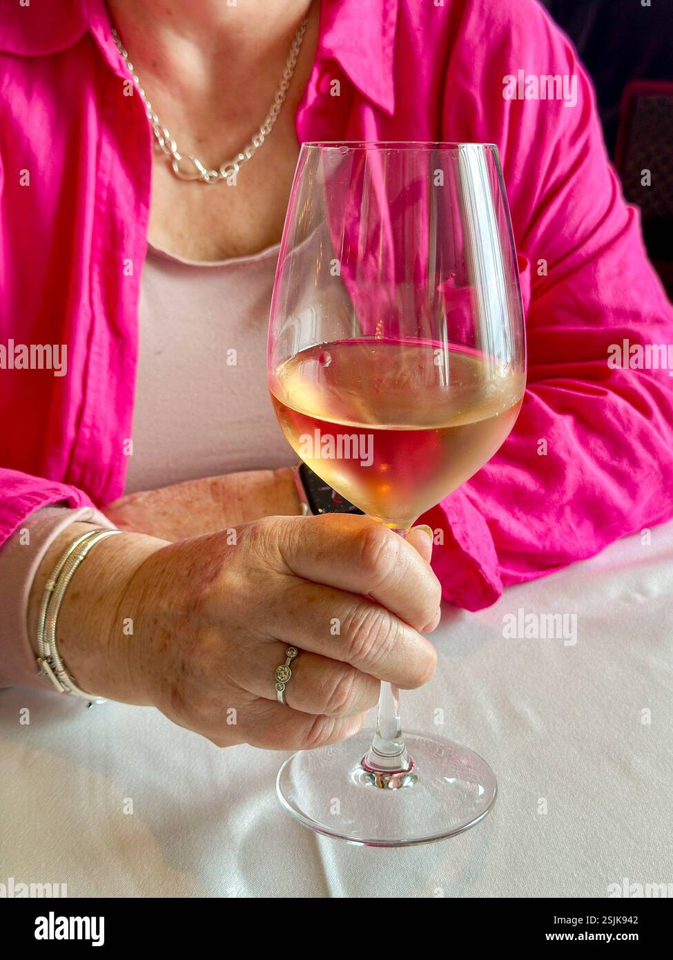 Person holding a large glass of rose wine in a restaurant - Smartphone Captured Stock Image