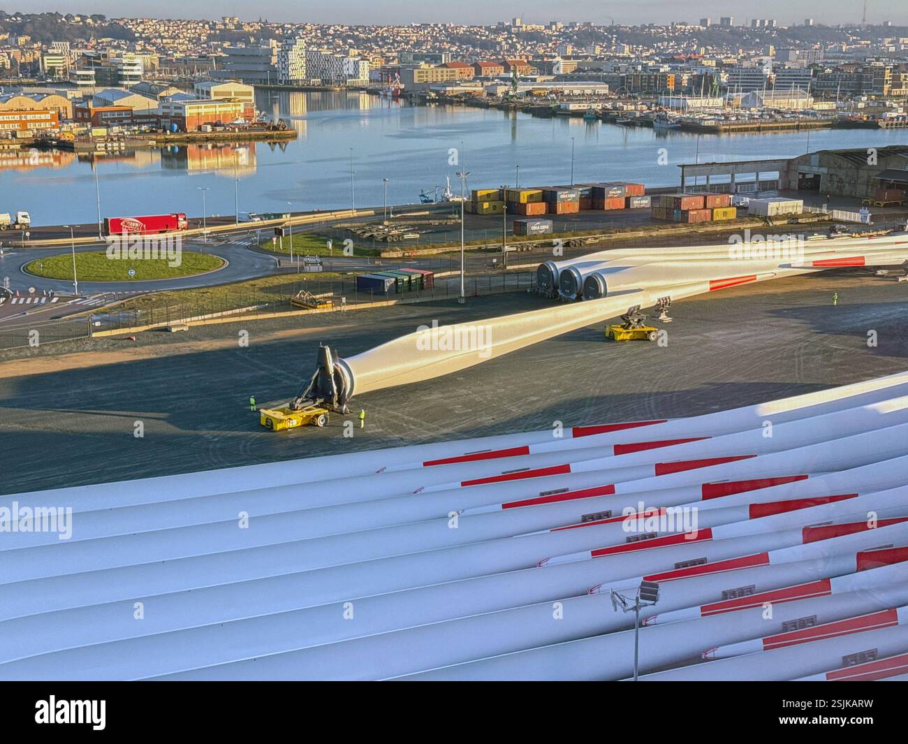 Le Havre, France, Europe - 16 January 2025: Workers using specialist remote controlled transporting equipment to move a large wind turbine blade - Smartphone Captured Stock Image