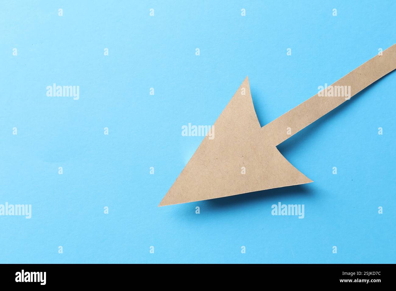 One kraft paper arrow on light blue background, top view. Space for ...