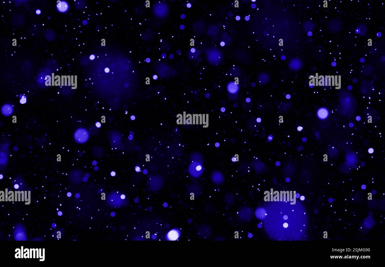 Vibrant blue glowing particles floating against a dark background Stock Photo
