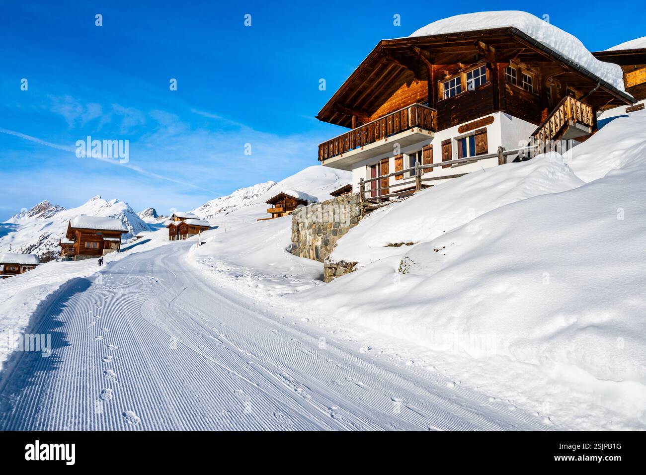 Winter snowy road with typical wooden houses in alpine village, Loetschental valley, Switzerland Stock Photo