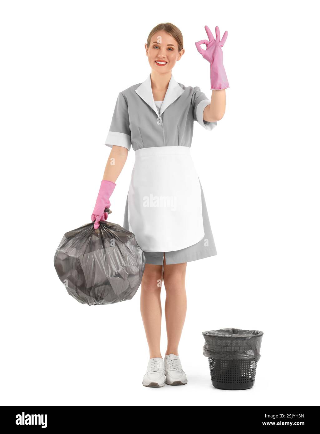 Pretty chambermaid with garbage showing OK gesture on white background Stock Photo