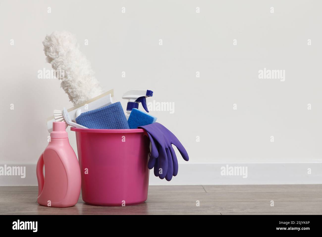 Bucket with cleaning products and rubber gloves on laminate floor ...