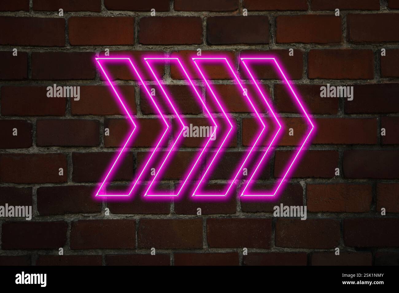 Pink neon arrow-shaped pointer on brick wall Stock Photo