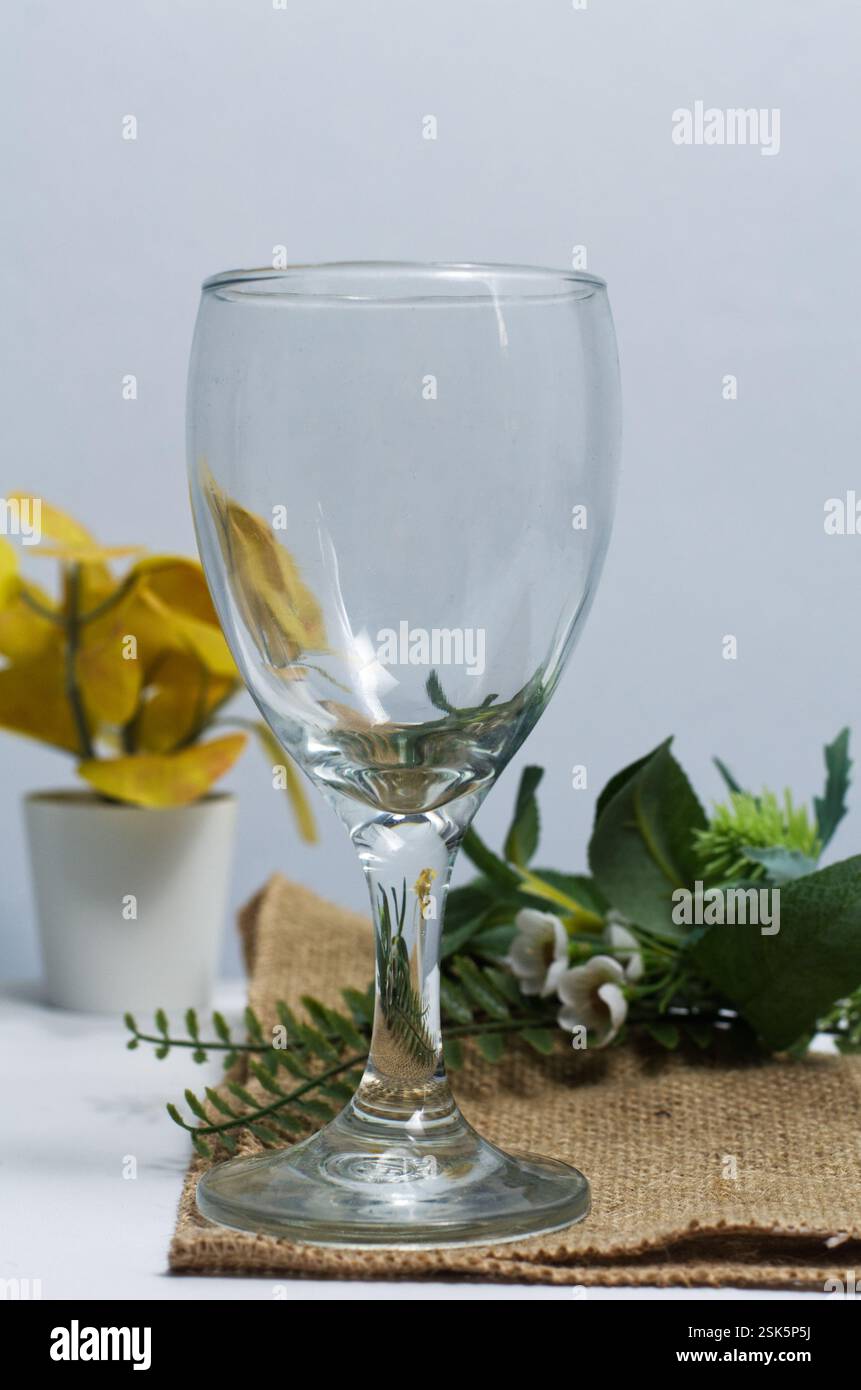 Empty Glass Goblet on Rustic Table with Floral and Botanical Elements Stock Photo