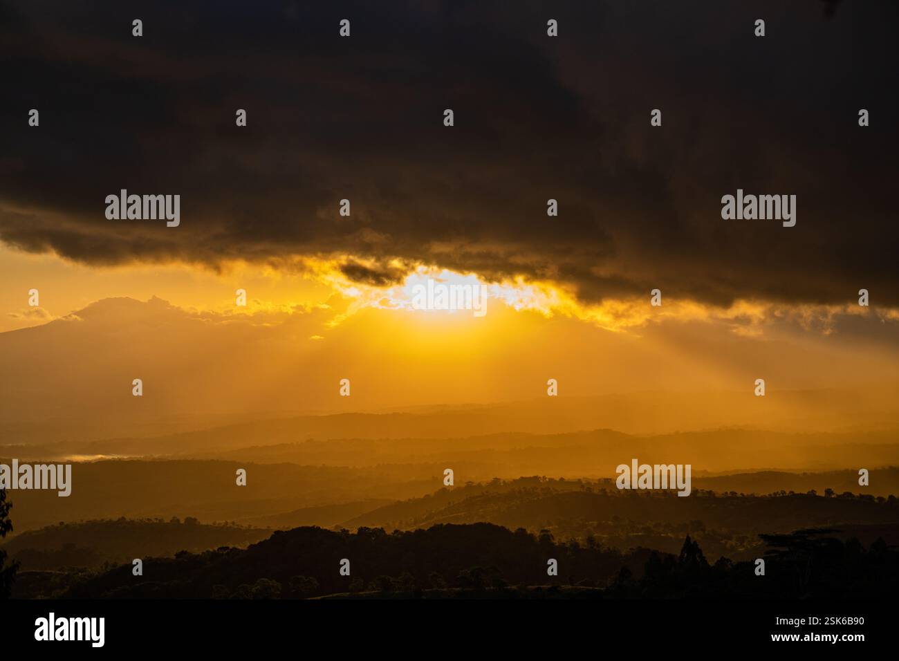 Golden Sunset Over Rolling Hills with Dramatic Dark Clouds and Sun Rays ...