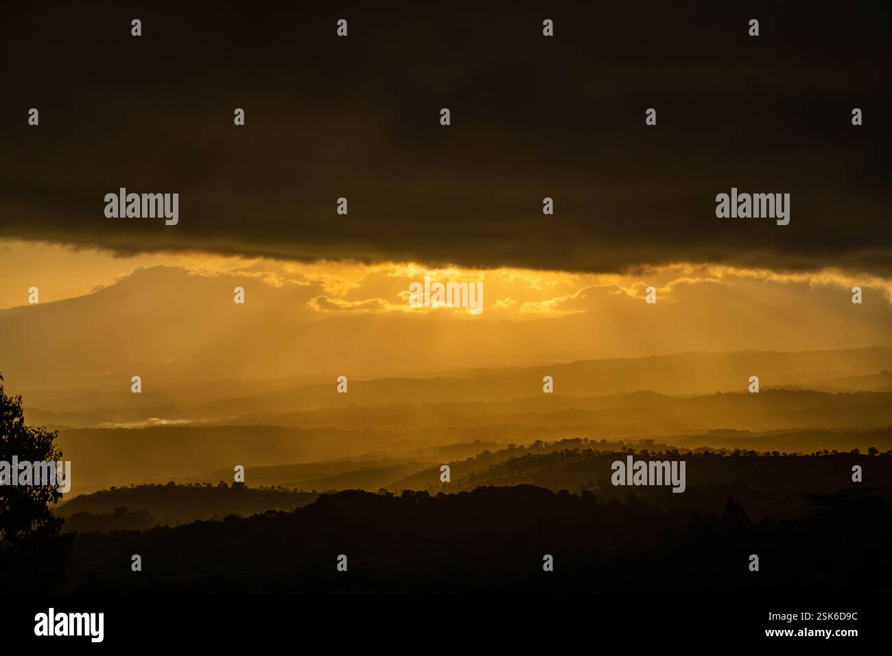 Golden Sunset Over Rolling Hills with Dramatic Dark Clouds and Sun Rays ...