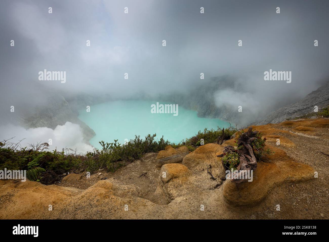 Clouds descending into Ijen volcano acidic crater lake on Java island Stock Photo