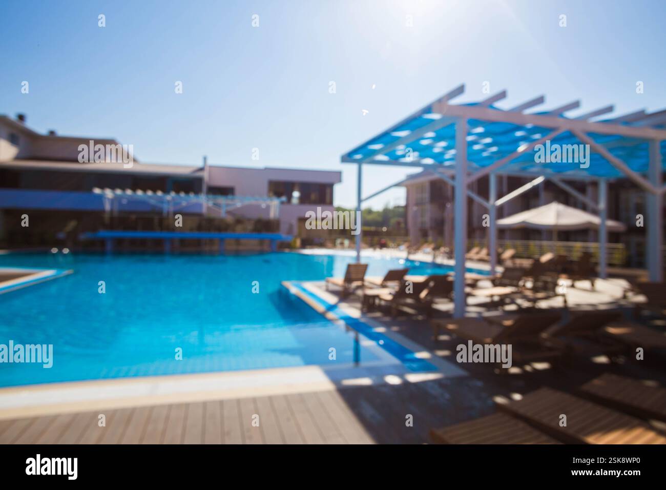 Sunny poolside relaxation area at a modern resort with lounge chairs ...
