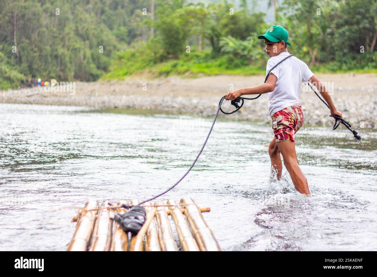 A Filipino boy leads his bamboo raft through the shallow parts of ...