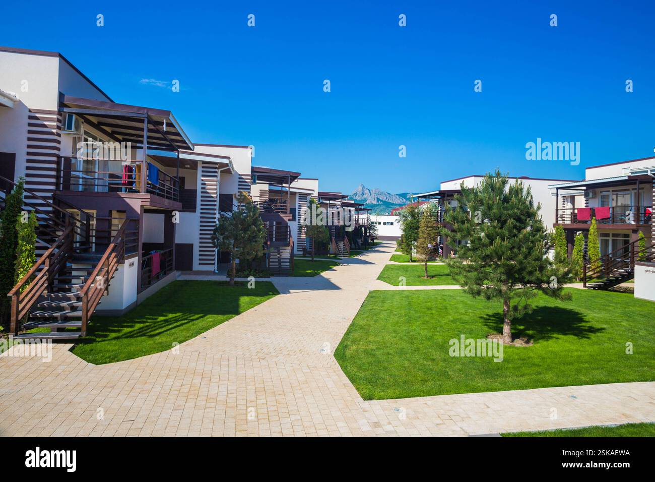 Modern residential complex with landscaped gardens and clear blue sky ...