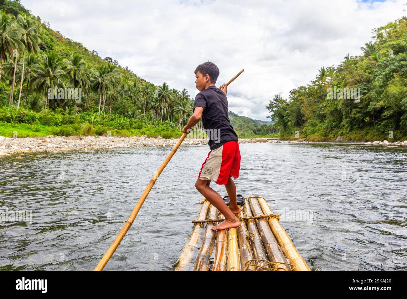 A Filipino boy leads his bamboo raft through the shallow parts of ...