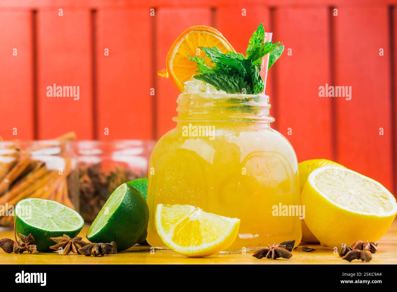 Refreshing citrus drink in a jar garnished with mint and orange on a wooden table Stock Photo