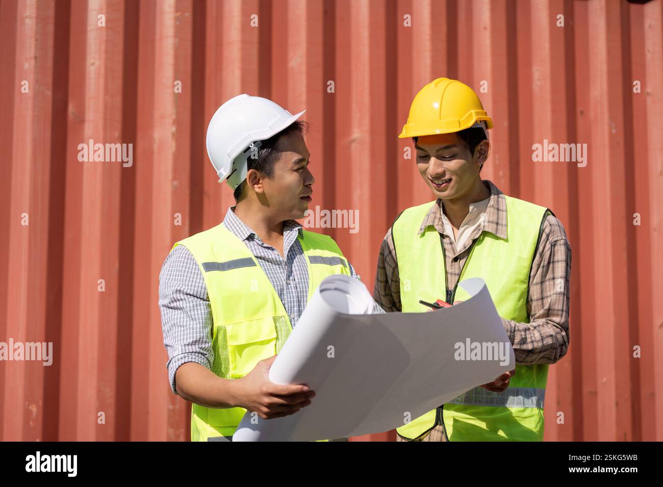 Engineers reviewing construction plans and discussing logistics on-site. Stock Photo