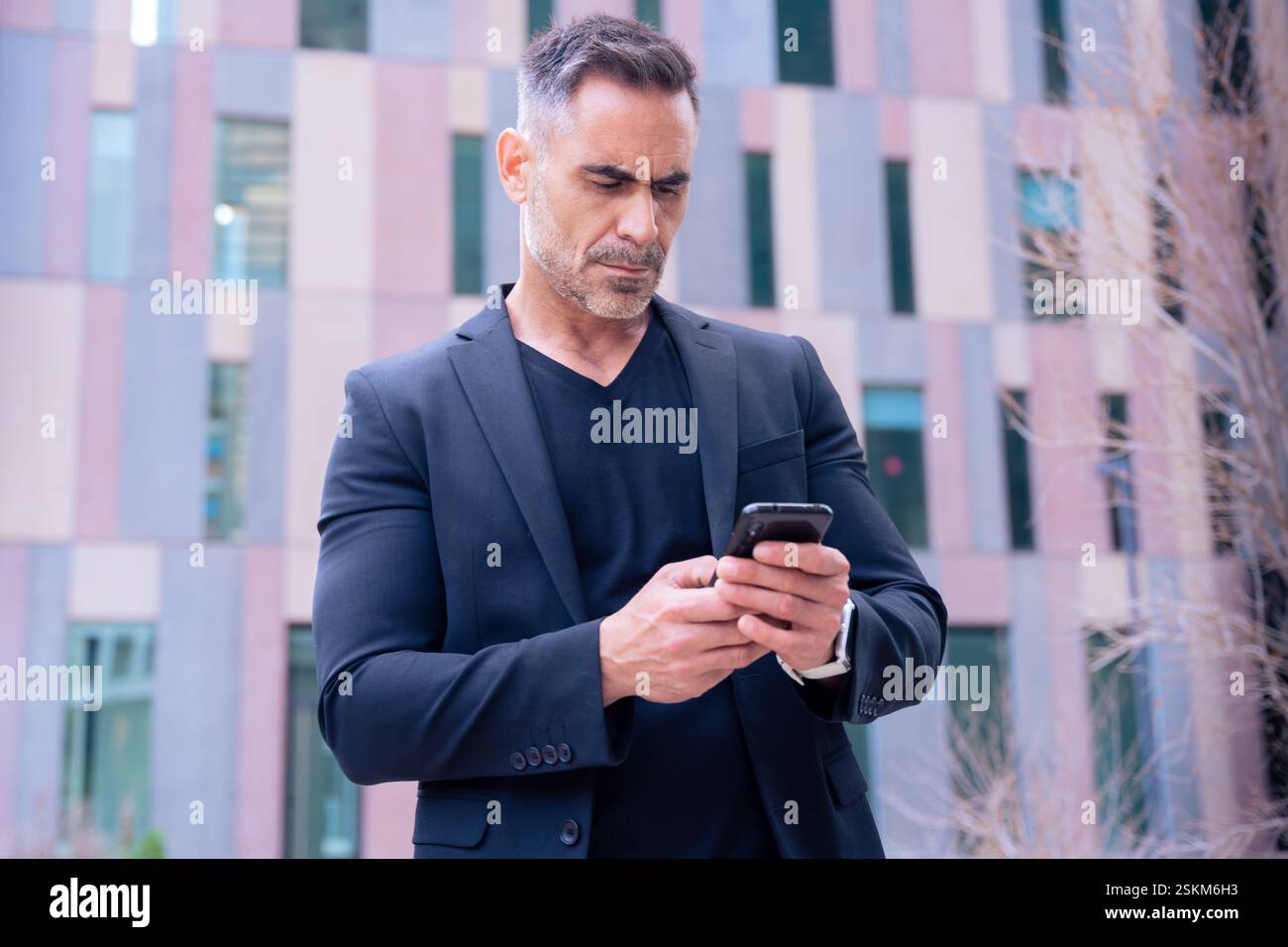 Confident businessman using smartphone outdoors, Stock Photo
