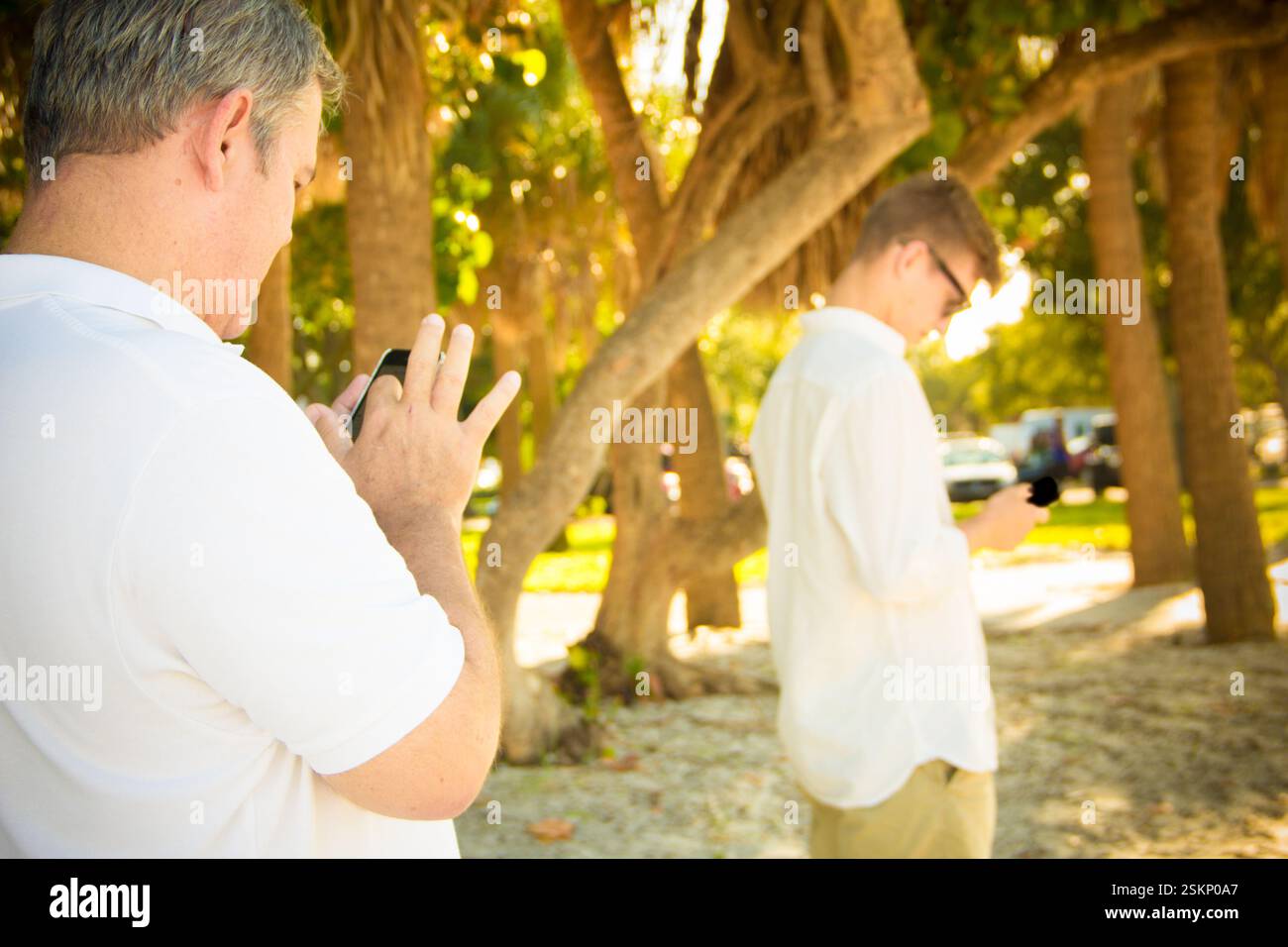 Two men standing outdoors using their mobile phones, Honduras Stock Photo