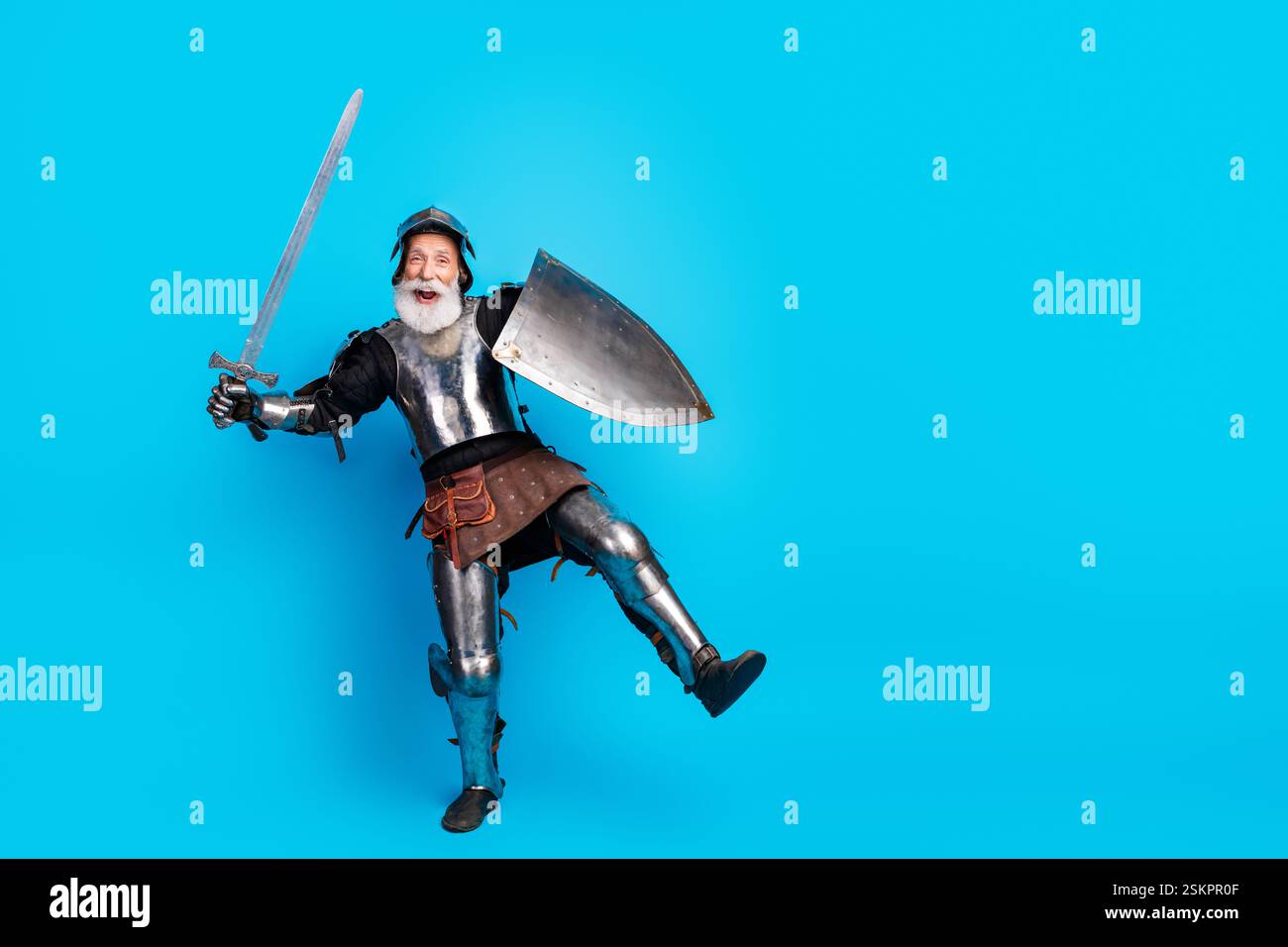 Cheerful retired knight posing in medieval armor with shield and sword ...
