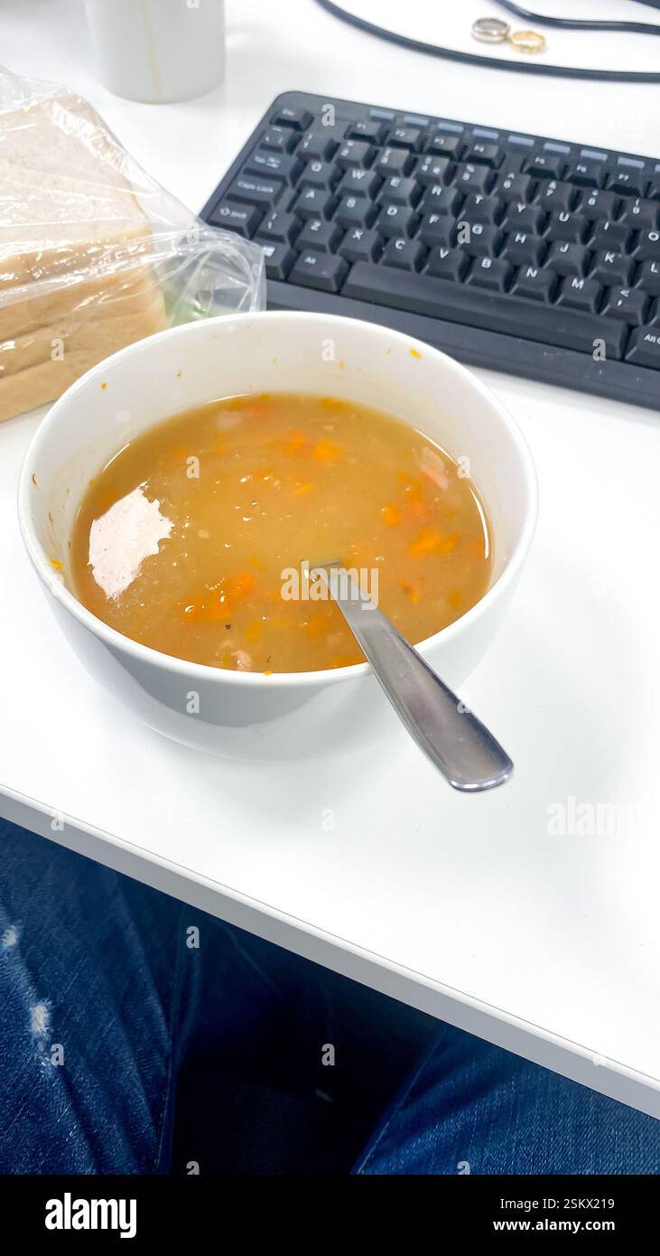 A bowl of soup, a working lunch sat at a desk in an office. - Smartphone Captured Stock Image