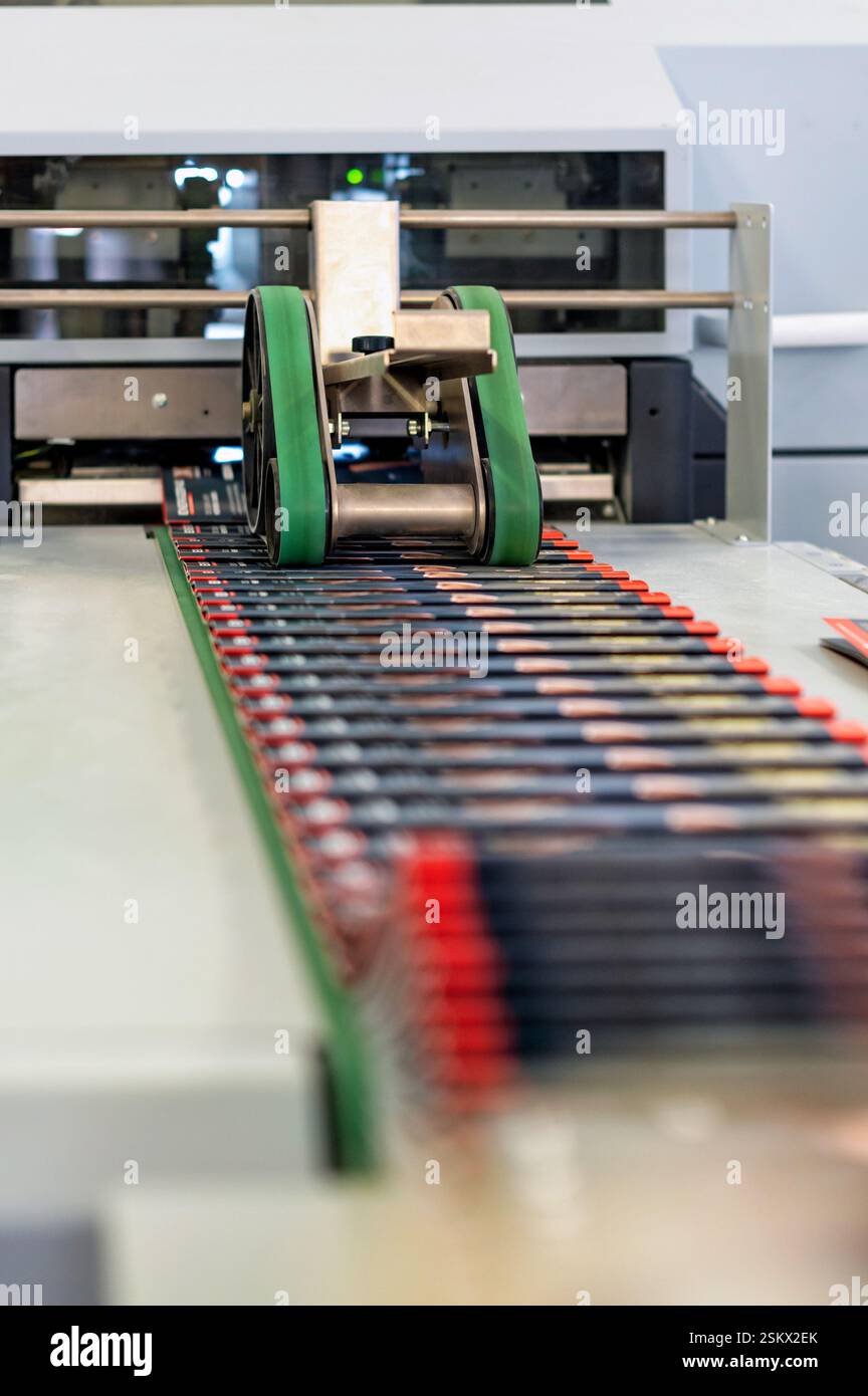 Industrial print finishing machine folding and sewing brochures in a print shop Stock Photo