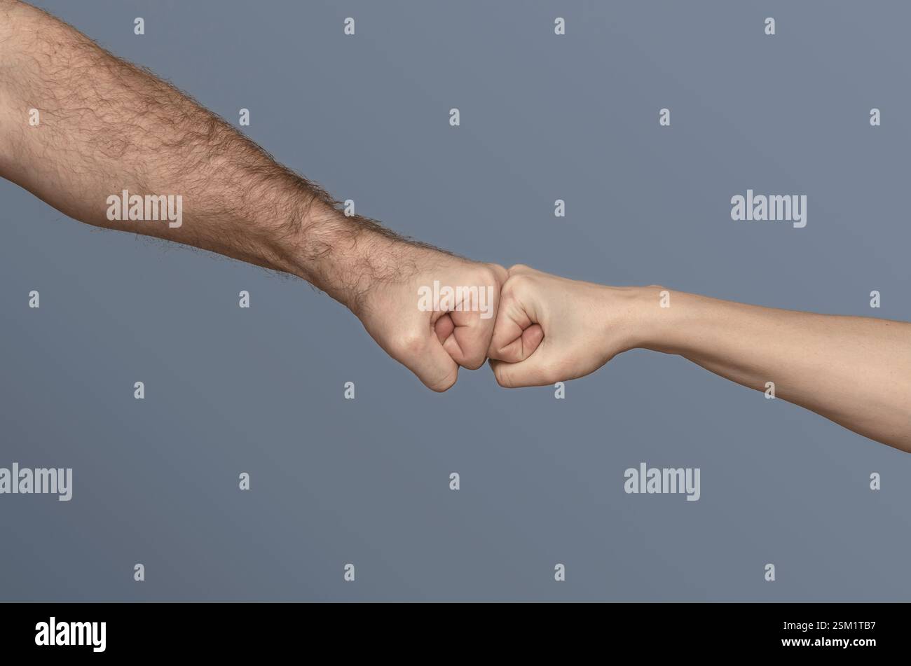 Male fist vs female fist. Concept of greeting, successful deal, partnership. Isolated on gray background Stock Photo