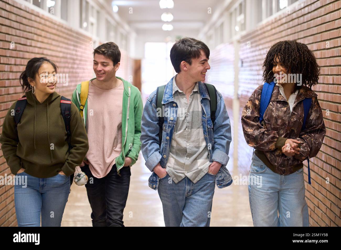 Happy students walking and talking in university hallway Stock Photo
